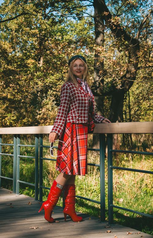 Free Fashionable woman in red plaid clothing stands confidently on a sunny outdoor walkway. Stock Photo