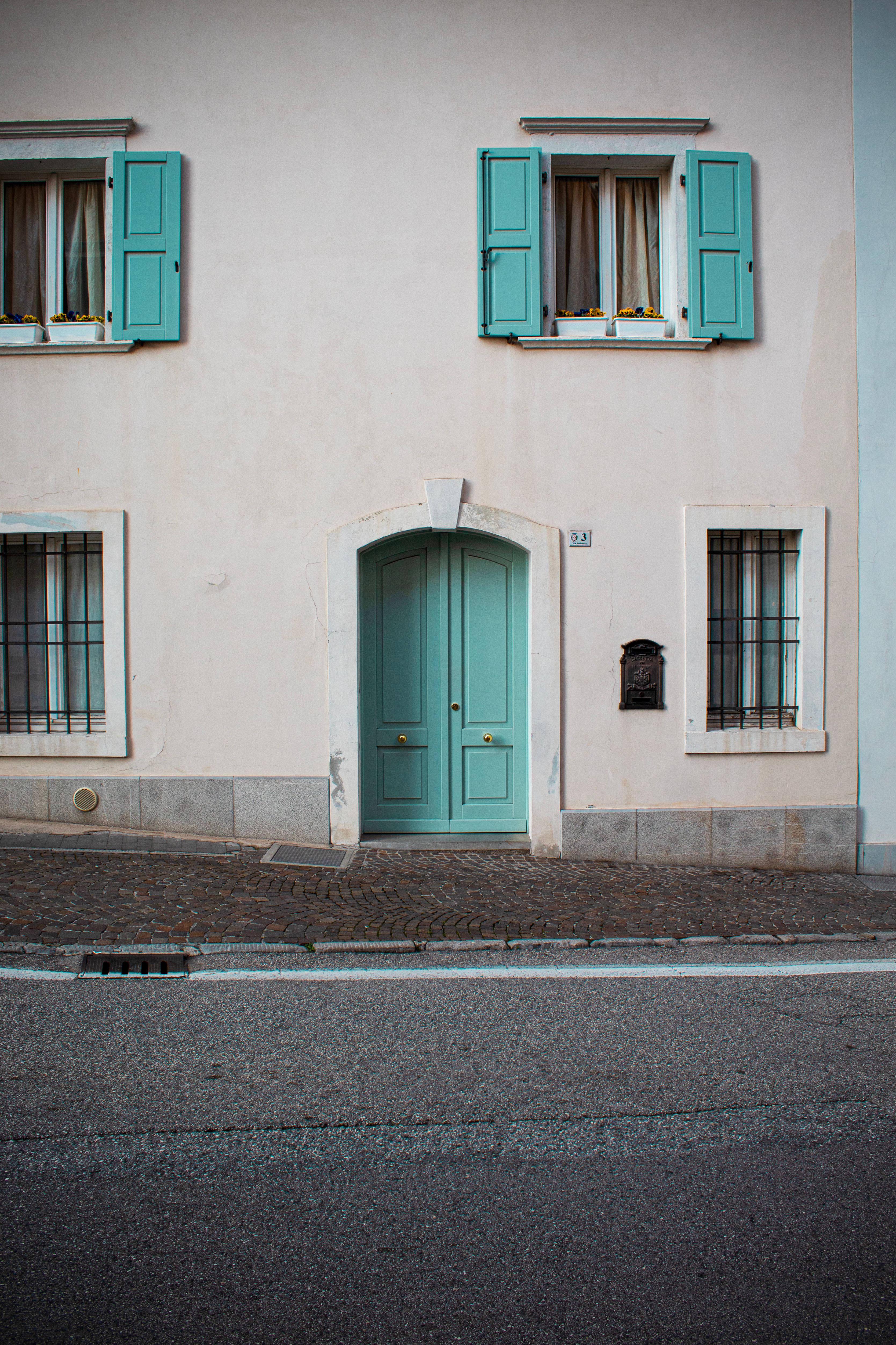 Elegant green door on a pastel building in San Daniele del Friuli, Italy.