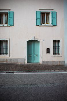 Elegant green door on a pastel building in San Daniele del Friuli, Italy.