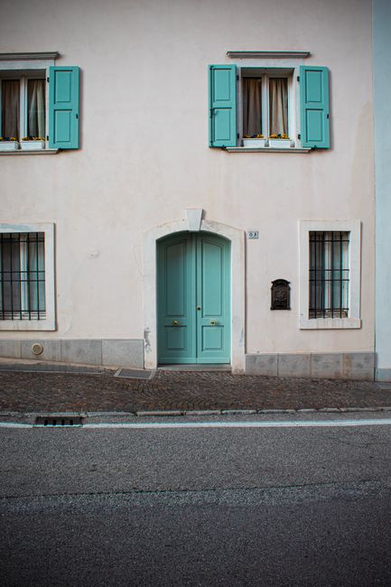 Elegant green door on a pastel building in San Daniele del Friuli, Italy.