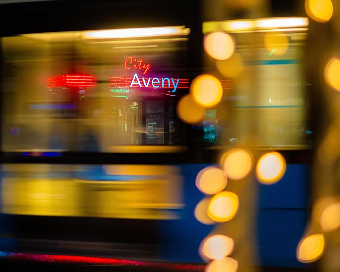 Neon signs smeared by motion blur on a night street &mdash; photo by Pasi M&auml;mmel&auml; on Pexels