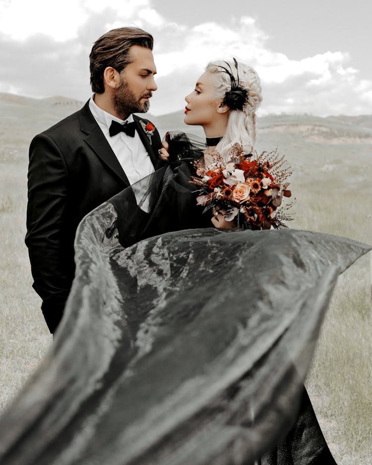 Man In Black Suit Holding Bouquet Of Flowers