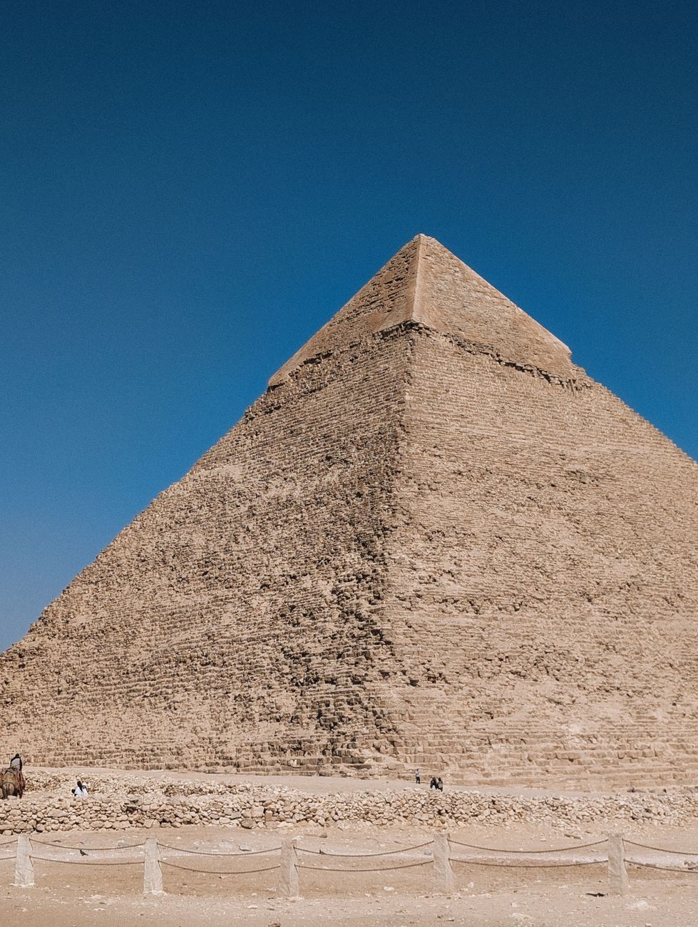 Een majestueus uitzicht op de Grote Piramide van Gizeh tegen een serene blauwe hemel in Egypte.