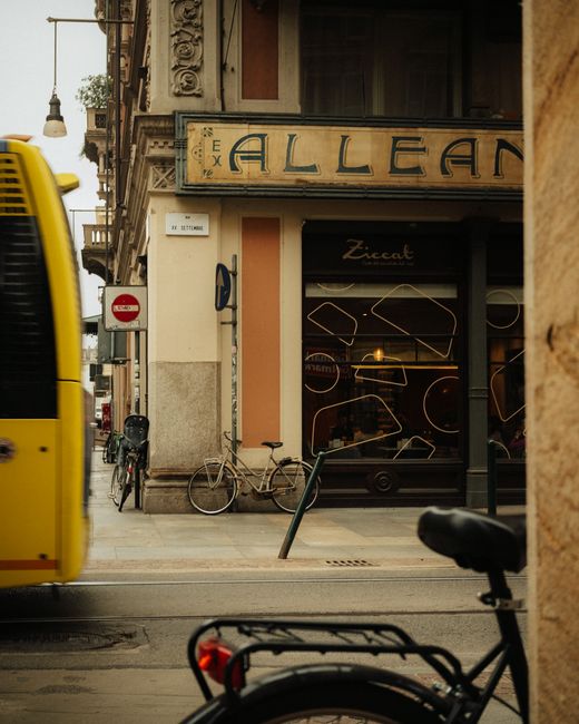 A cozy Turin street with a vintage café, bicycles, and passing tram in Piedmont, Italy.