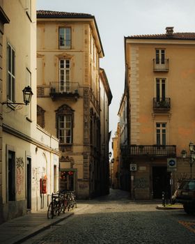 Explore a picturesque narrow street in Turin, Italy, showcasing classic architecture under the warm daylight.