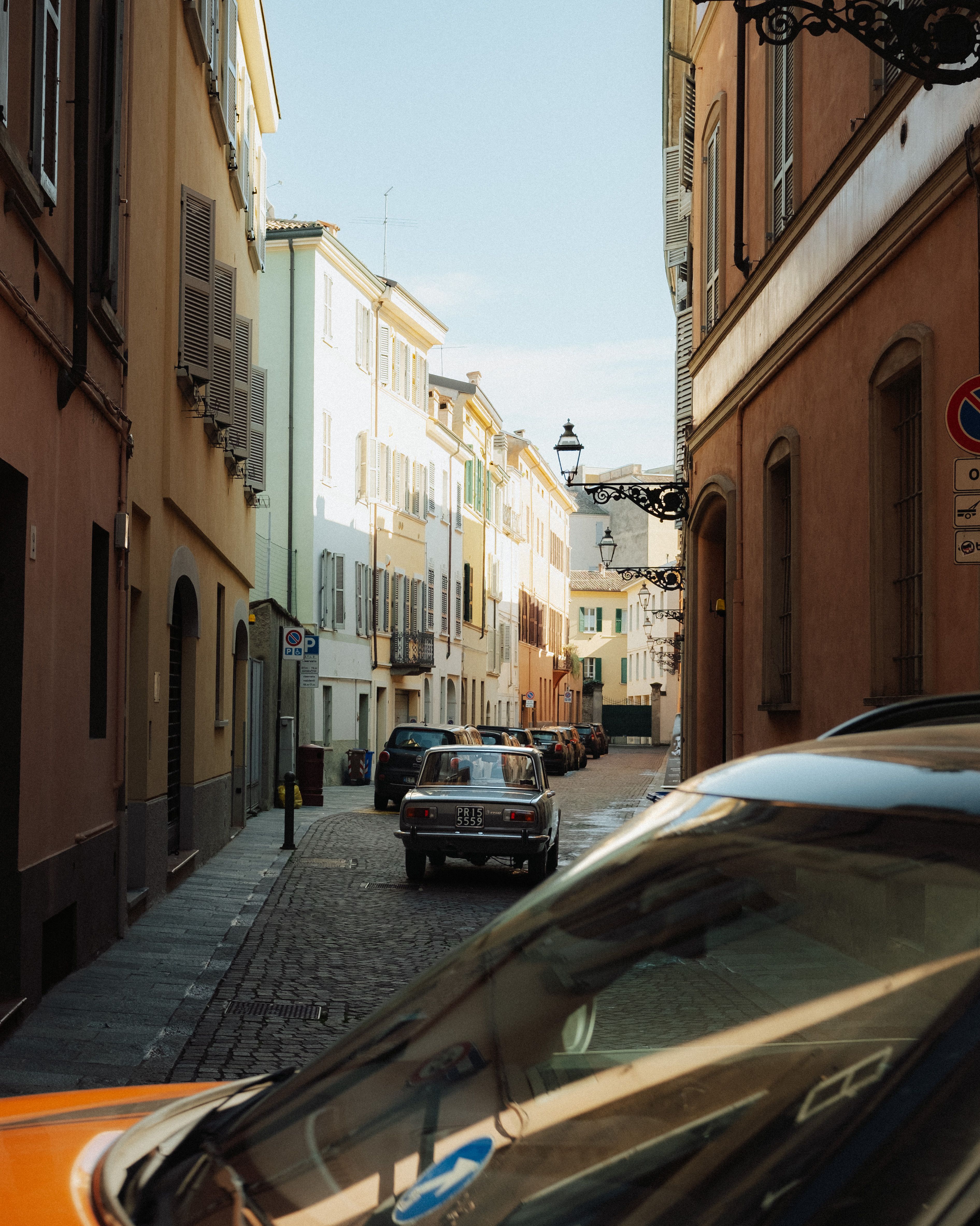 Charming view of a vintage car on a sunlit street in Parma, Italy.