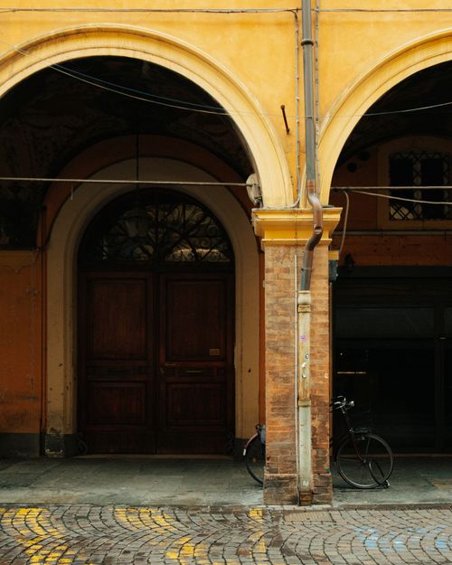 Free Vintage arched doorway with bicycle in Modena, Italy showcasing classic architecture. Stock Photo