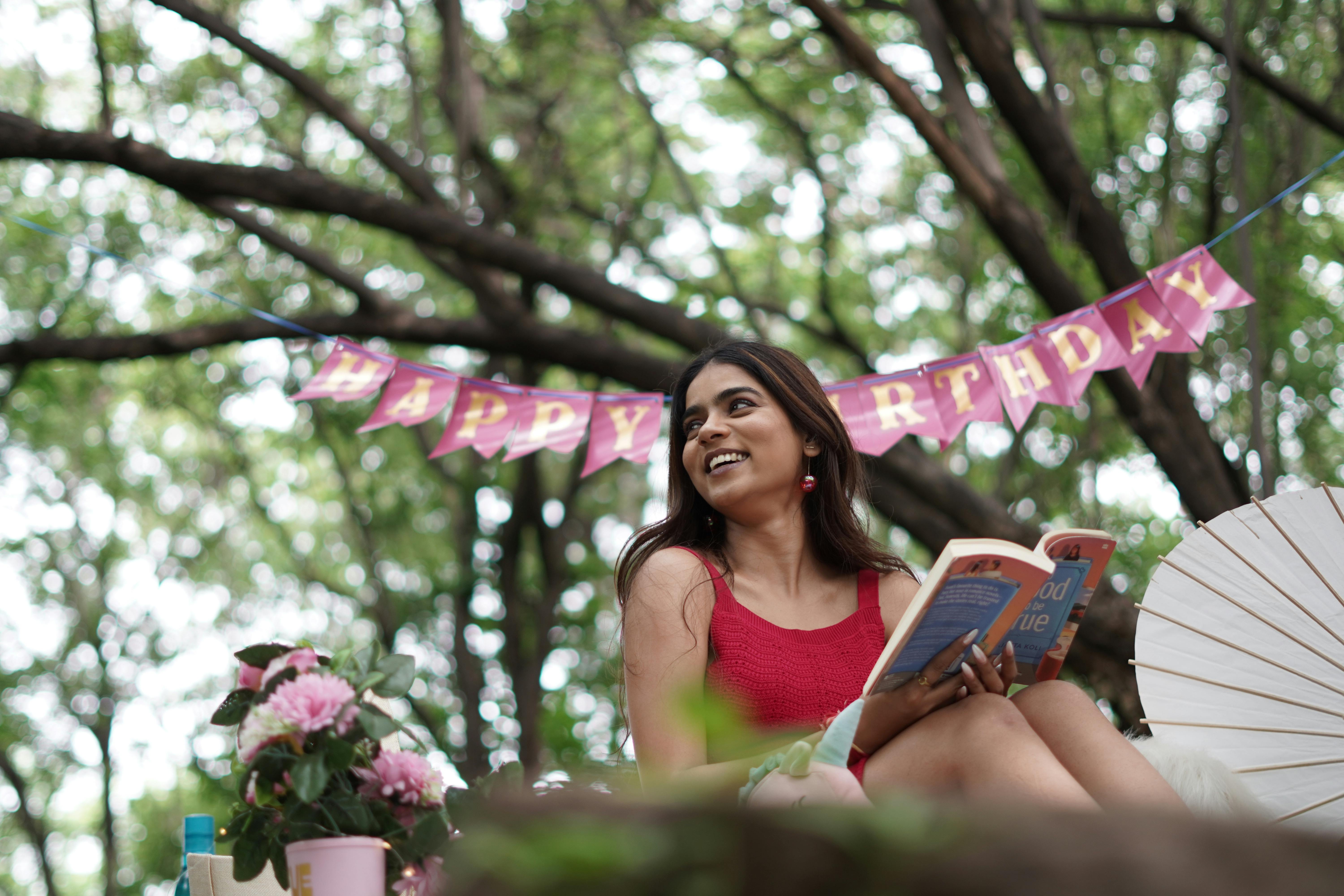 Δωρεάν Νέα γυναίκα που γιορτάζει τα γενέθλια σε εξωτερικούς χώρους με βιβλίο και διακοσμήσεις. Φωτογραφία από στοκ φωτογραφιών