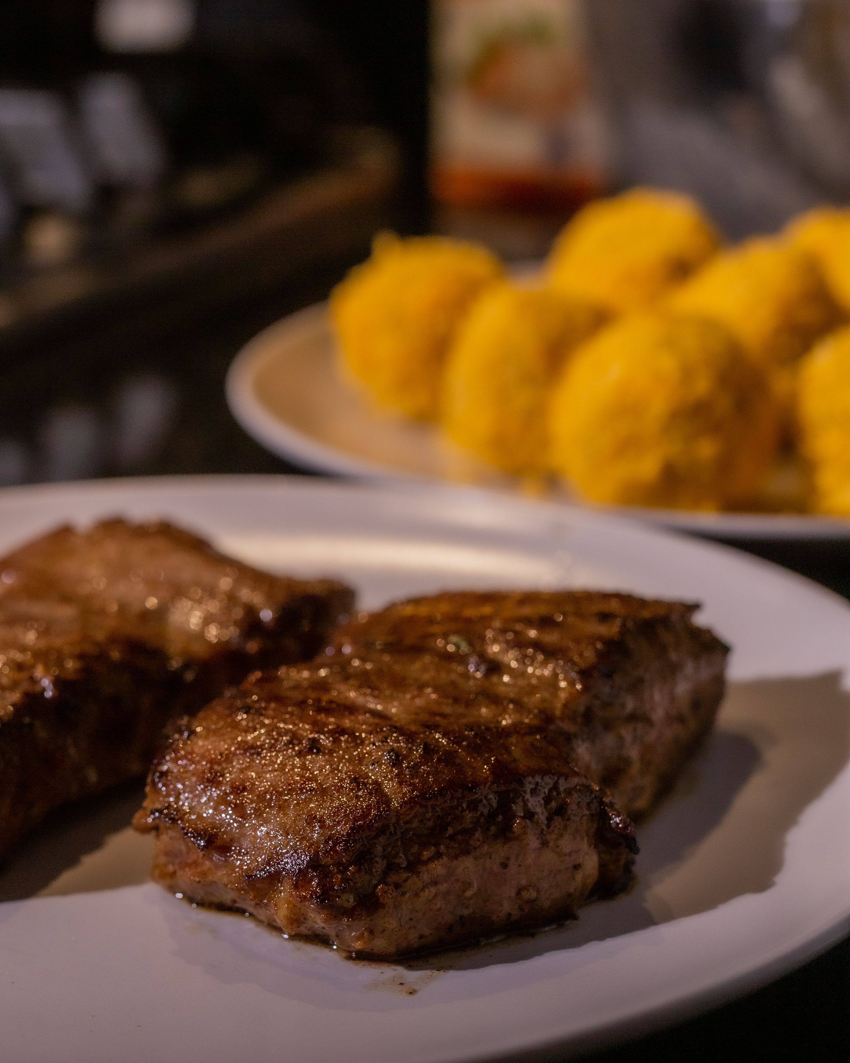Deliciously grilled beef steak with cornball side dish on a plate, perfect for gourmet recipes.