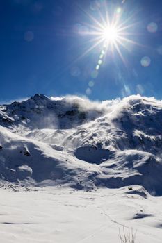Scenic view of snow-covered mountains under a clear blue sky in Salzburg, Austria, with the sun shining brightly.
