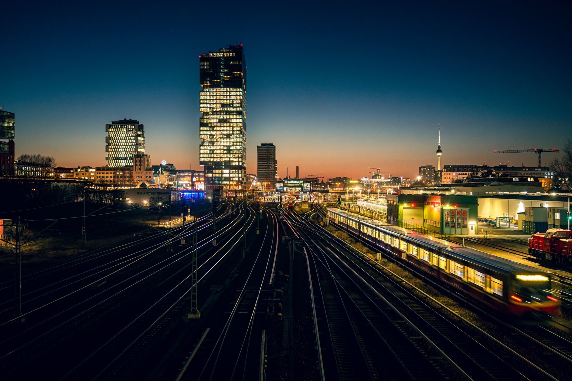 Captivating view of Berlin's skyline and railway network at dusk, featuring iconic architecture and vibrant city life.