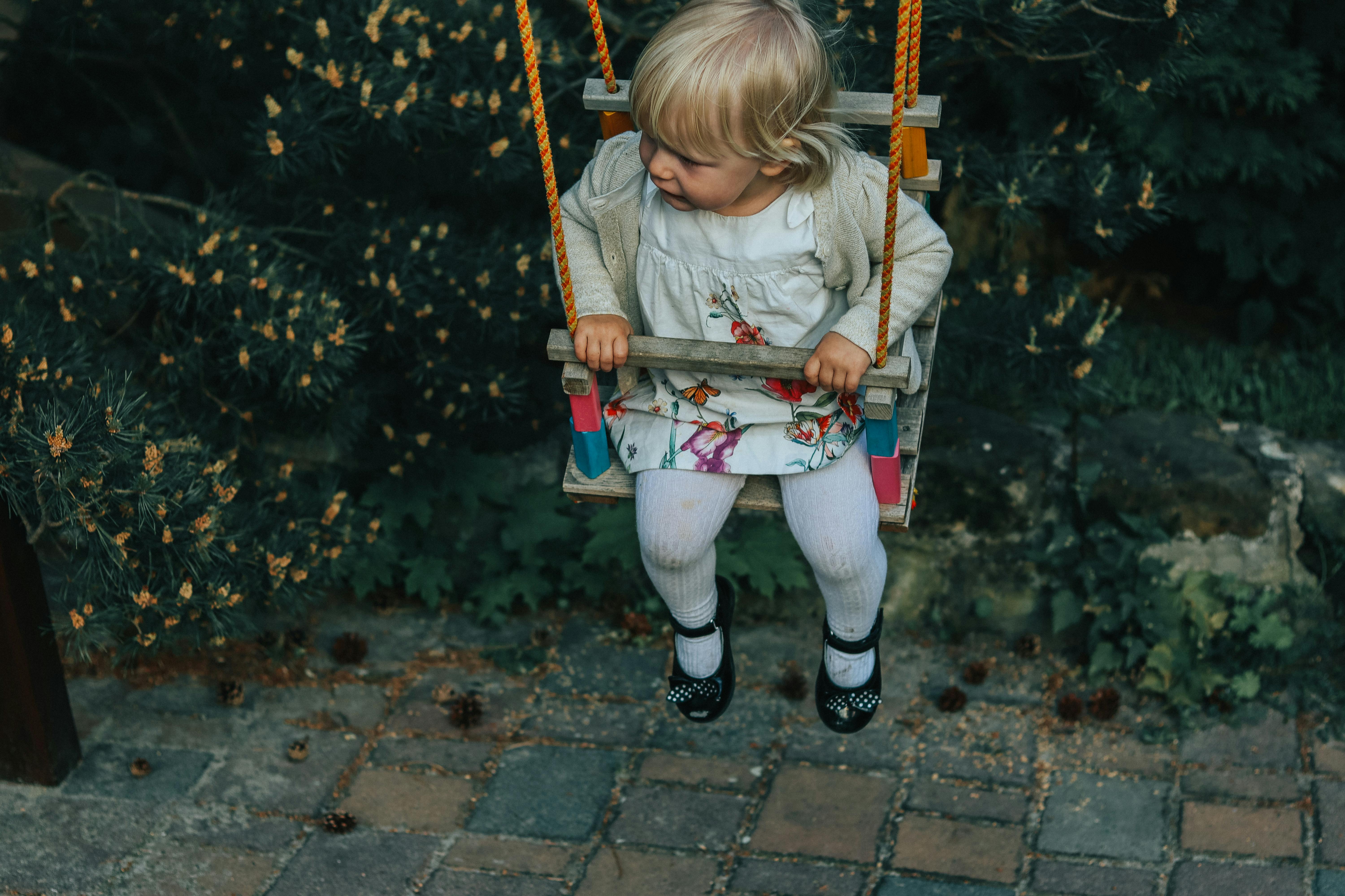 girl in white jacket riding on swing