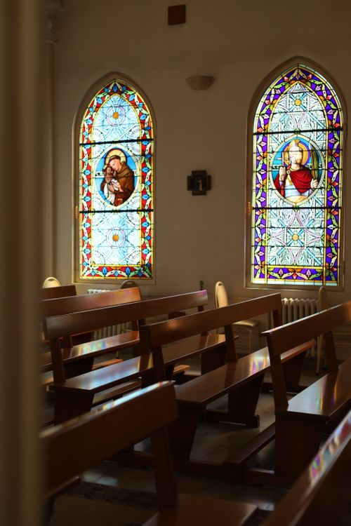 Free Peaceful church interior with beautiful stained glass windows depicting religious figures. Stock Photo