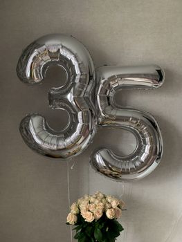 Silver foil balloons displaying '35' alongside a delicate bouquet of roses.