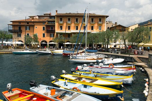 Explore a picturesque lakeside village in Italy with colorful boats docked at the serene harbor.