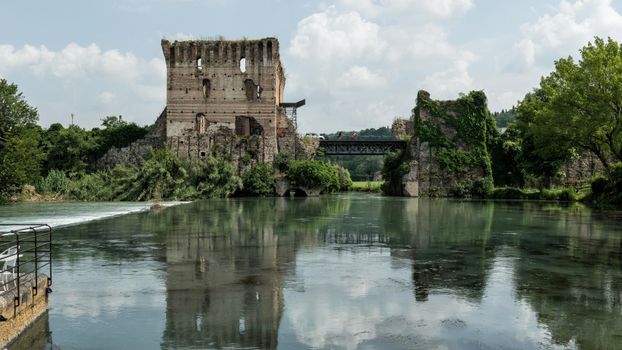 Discover the serene beauty of ancient ruins by the river in Valeggio sul Mincio, Italy.