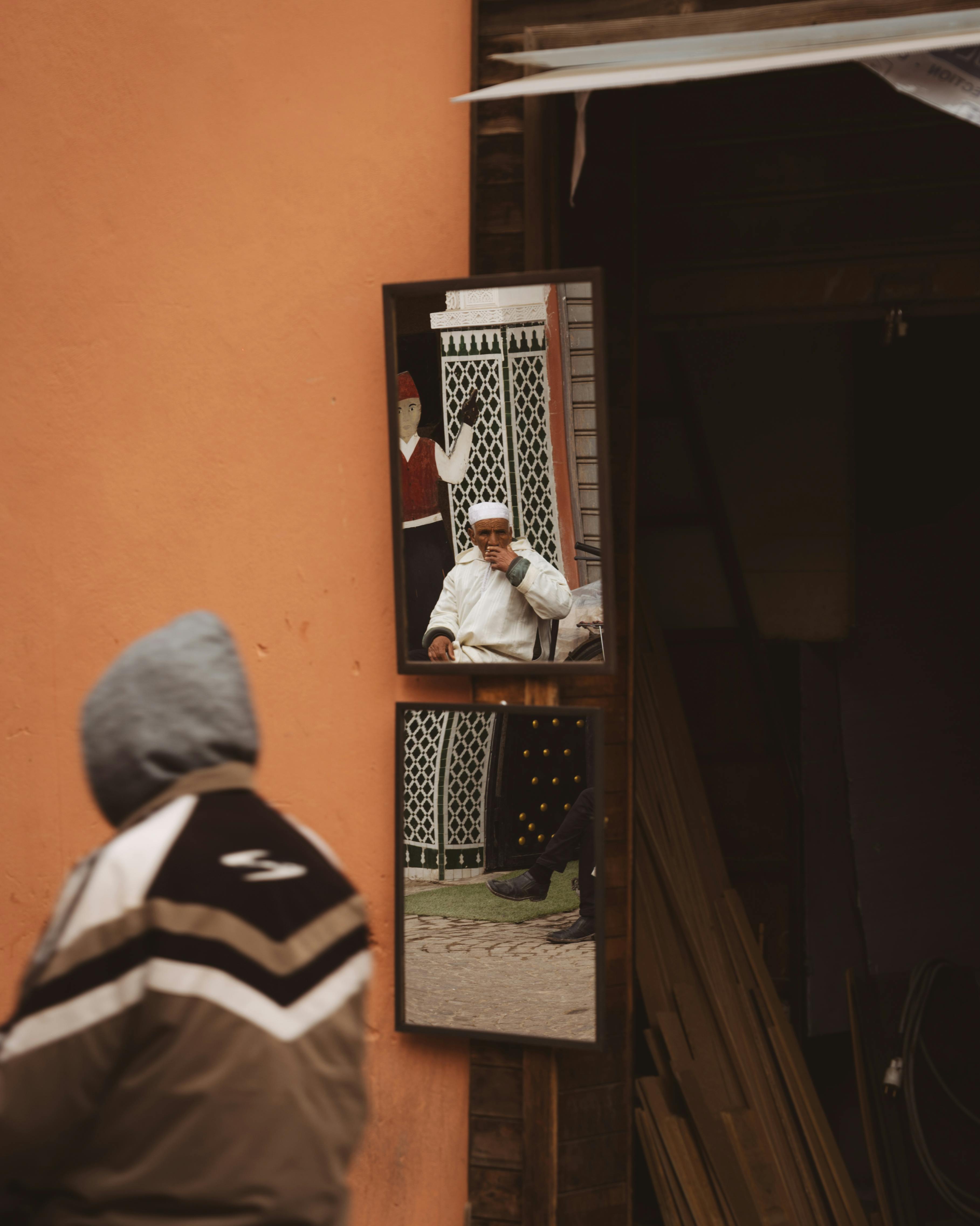 Ücretsiz Şehir ortamında bir sokak aynasında yansıyan bir insan, şehir hayatının özünü yakalıyor. Stok Fotoğraflar