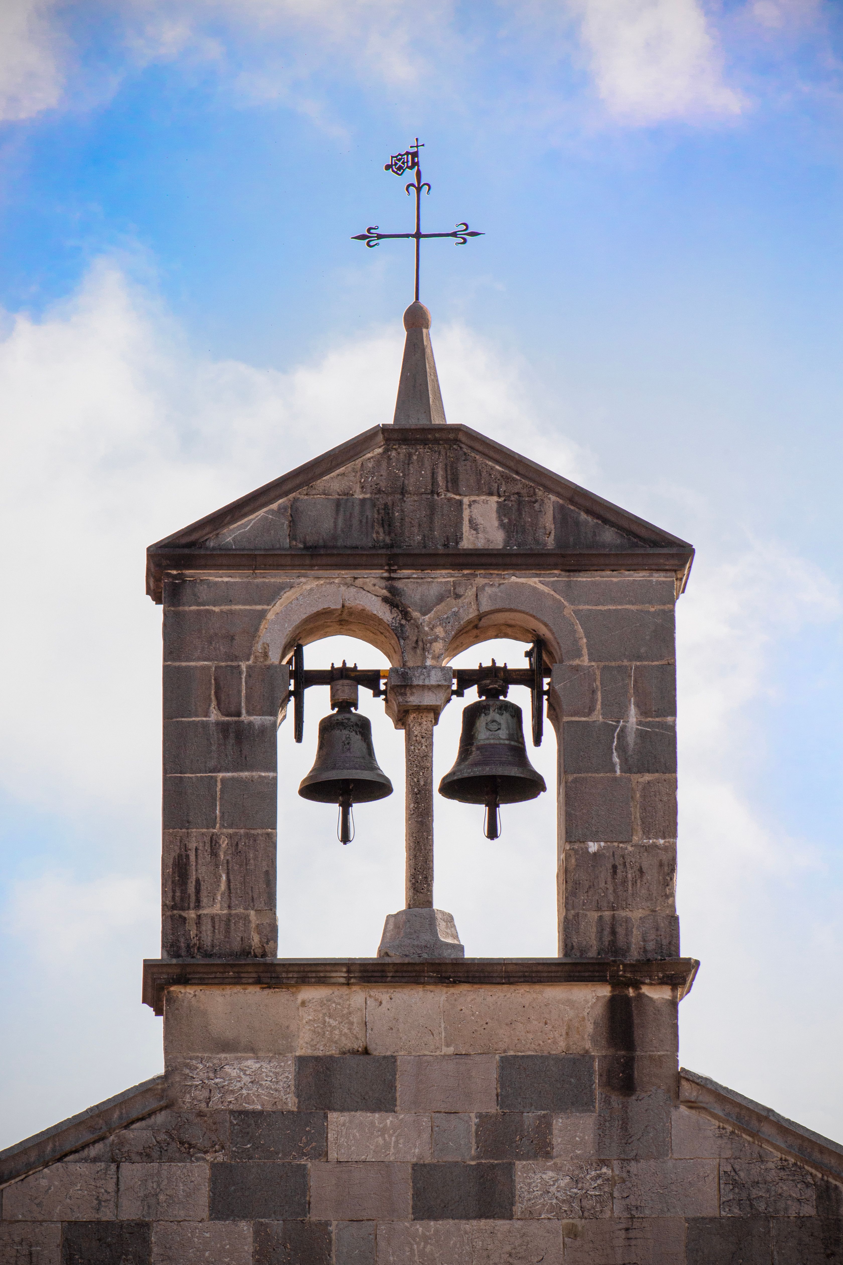 Close-up of a historic bell tower with blue sky in San Daniele del Friuli, Italy.