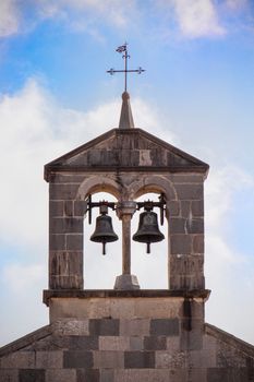 Close-up of a historic bell tower with blue sky in San Daniele del Friuli, Italy.
