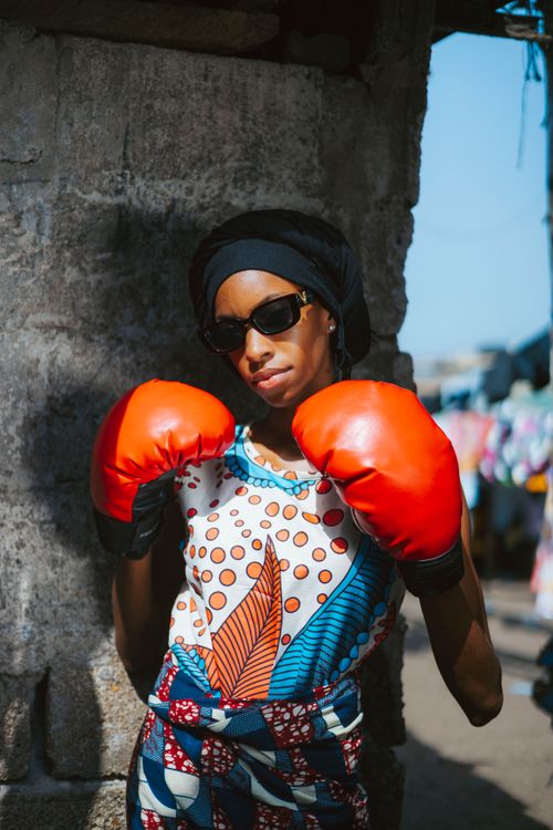 Free A stylish woman in red boxing gloves poses confidently on a sunny Monrovia street. Stock Photo