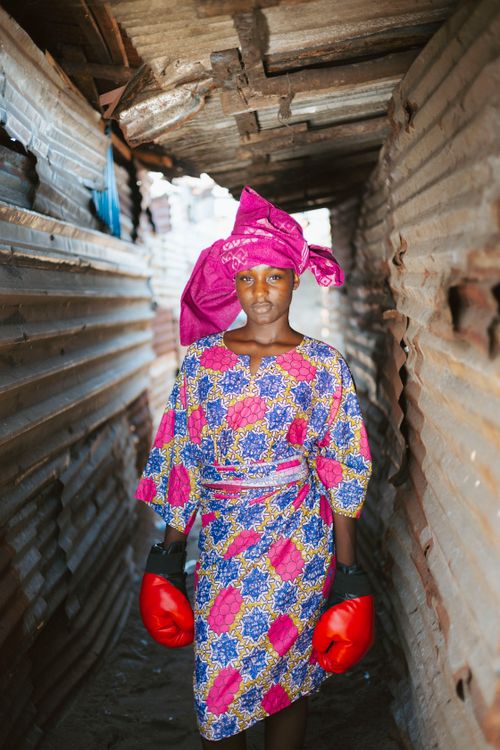 Free Woman in traditional African attire and boxing gloves in Monrovia alley. Stock Photo