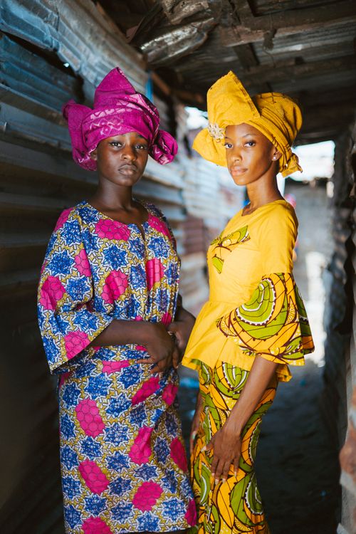 Free Two women in vibrant traditional attire pose in an alley in Monrovia, showcasing cultural fashion. Stock Photo