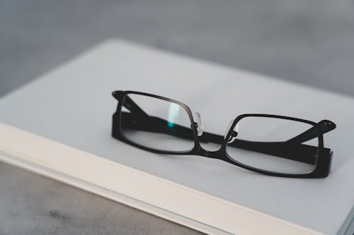 Kostenlos Schwarz Gerahmte Brille Auf Weißem Tisch Stock-Foto