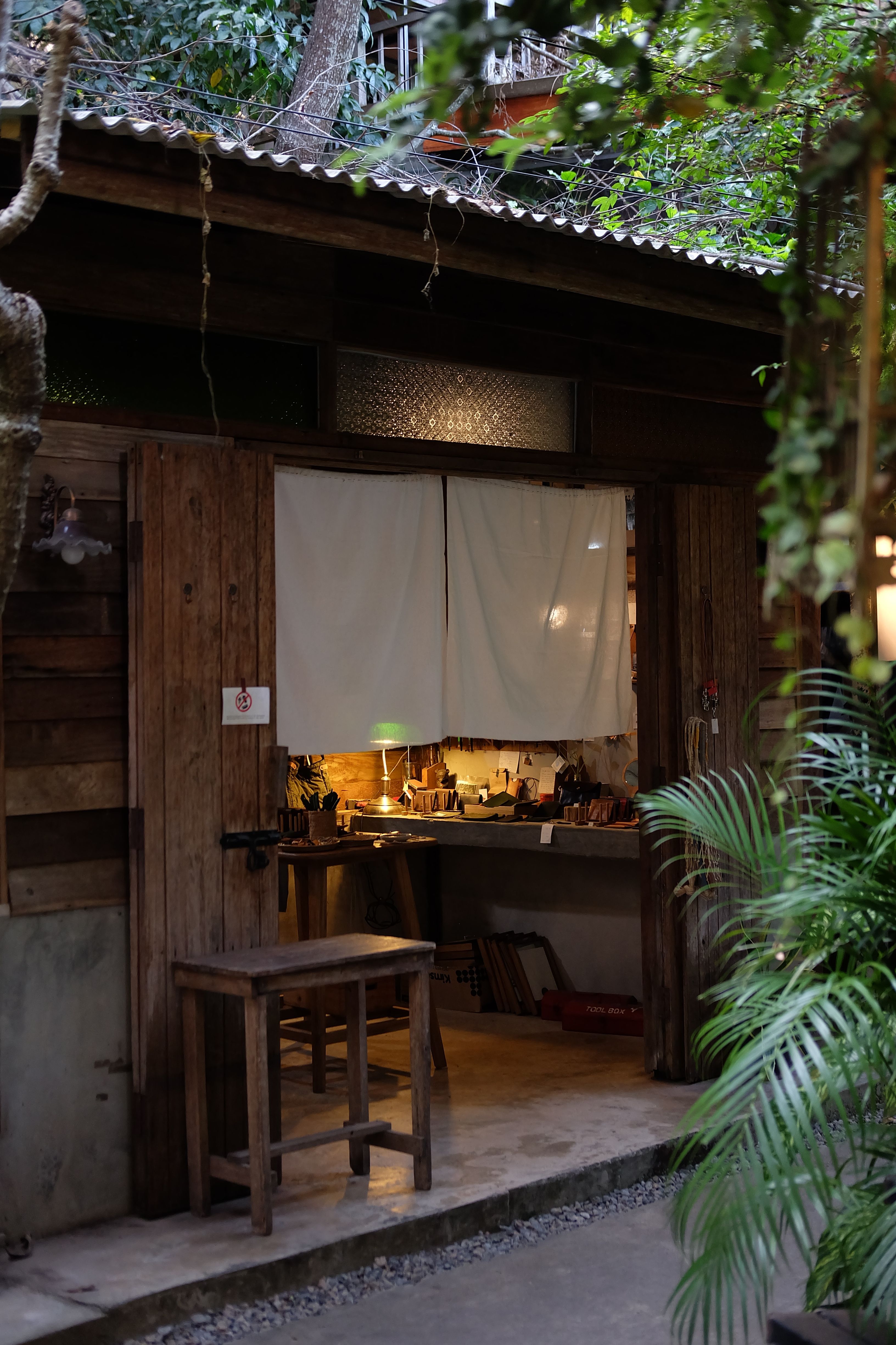 A charming and cozy outdoor home workshop nestled within a lush forest environment.