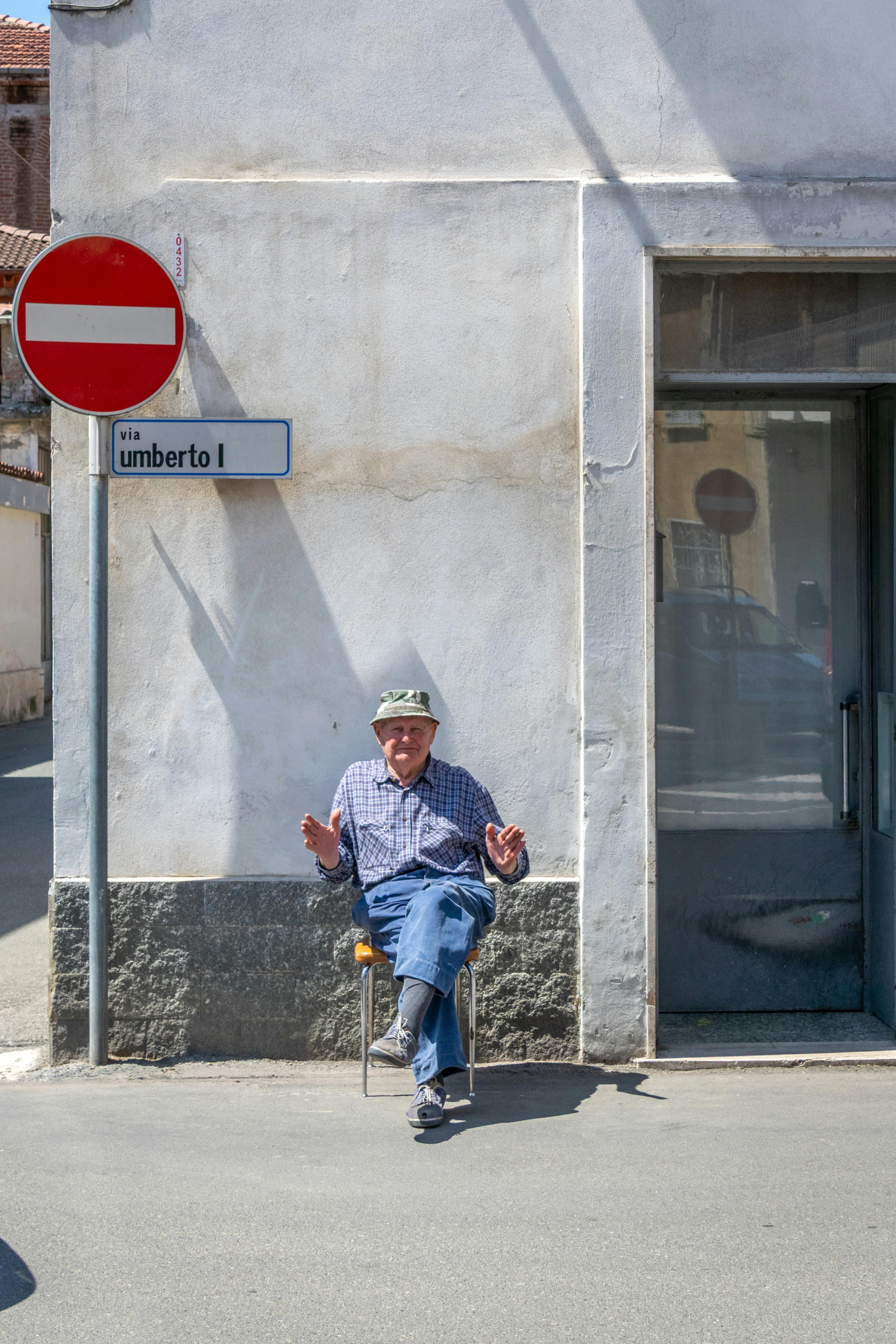 grátis Homem idoso sentado na sombra, na Via Umberto I, em Castellazzo Bormida, Itália, em um dia ensolarado. Foto profissional