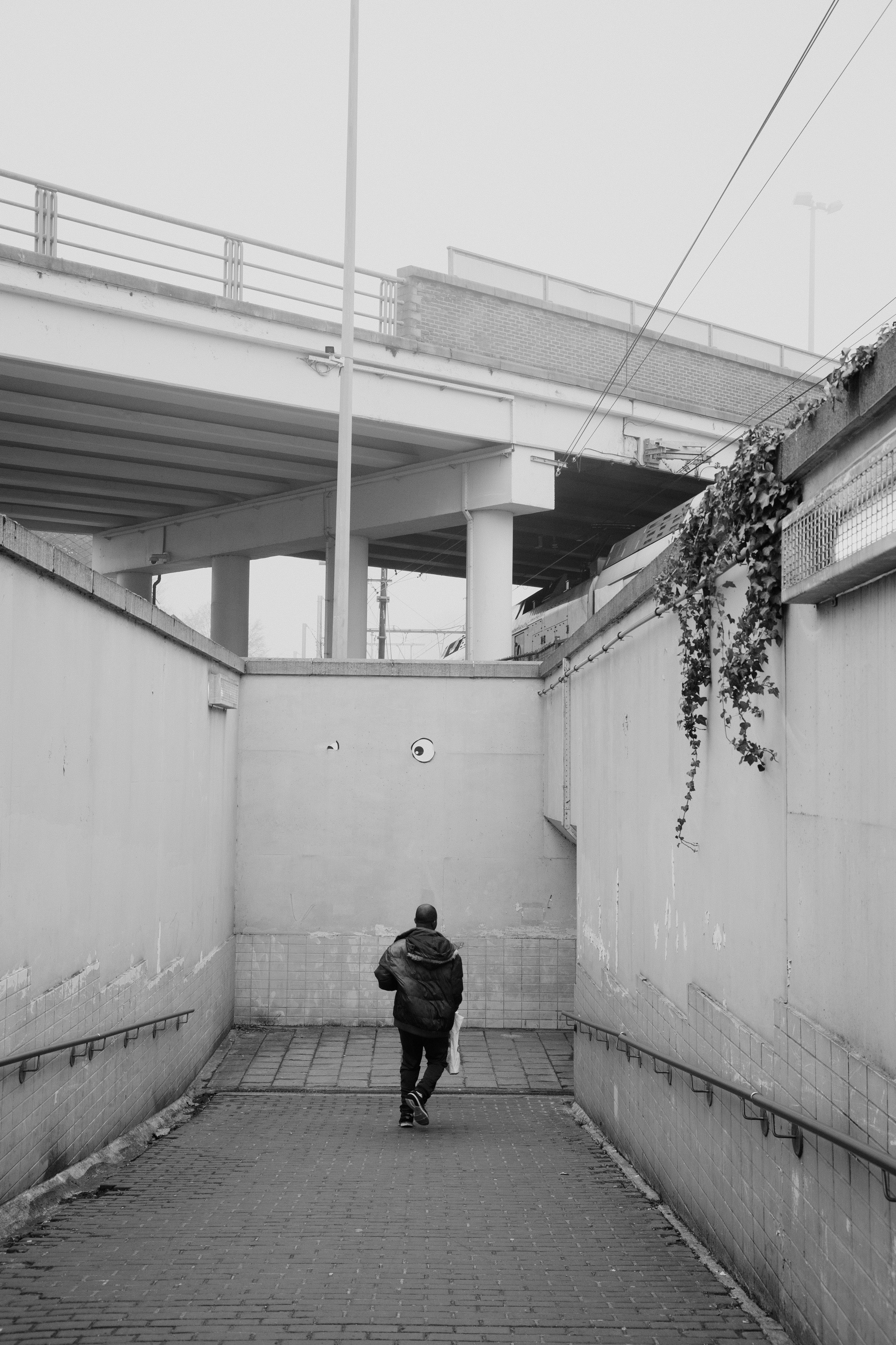 De franc Un home camina per un pas subterrani urbà de formigó a Hasselt, Bèlgica, capturat en blanc i negre. Foto d'estoc