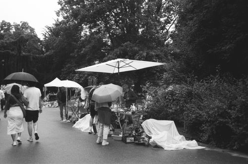 Free Black and white photo of an outdoor flea market in Nancy, France in the rain, with people using umbrellas. Stock Photo