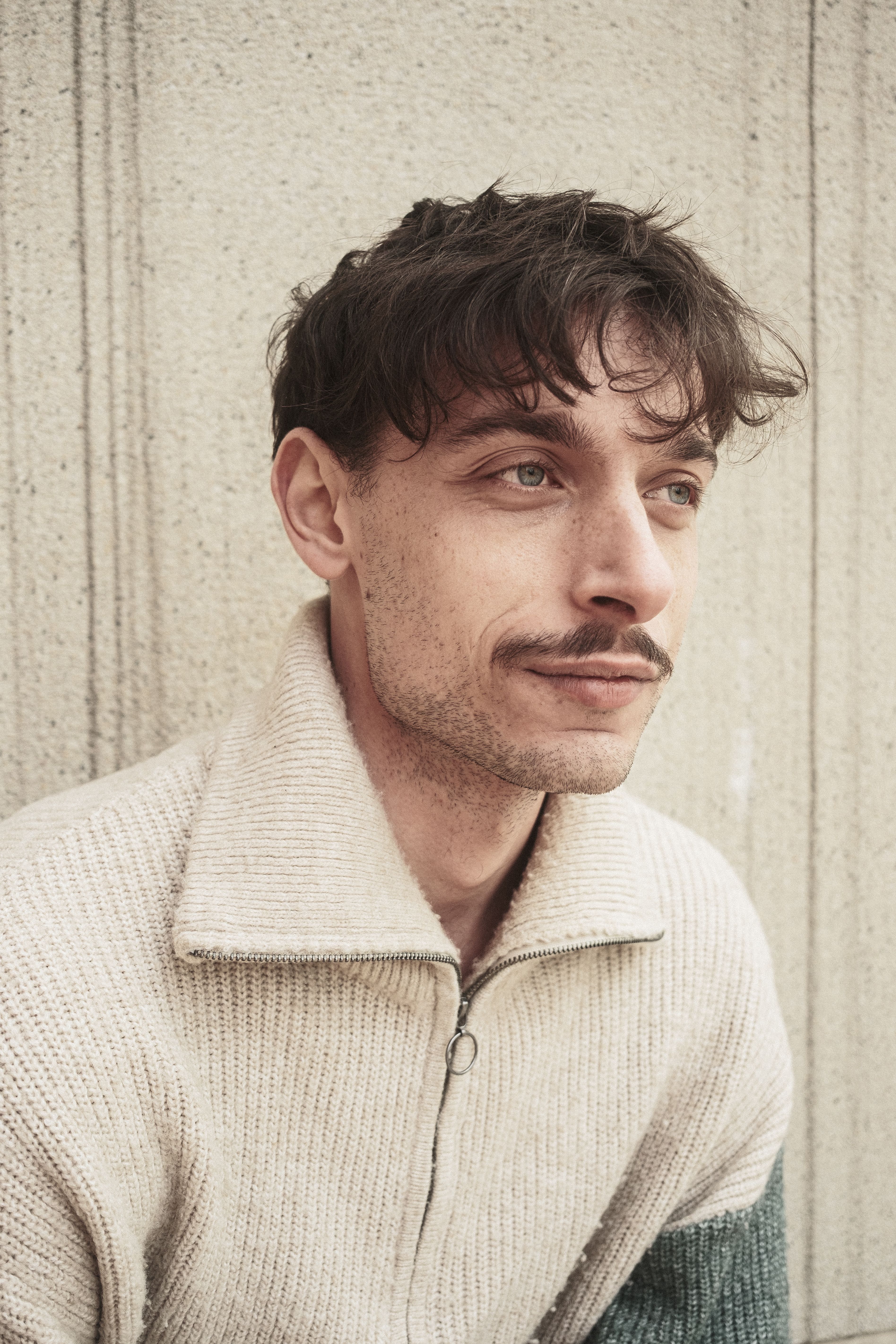 Portrait of a man with a mustache in a cozy sweater, exuding a relaxed vibe.