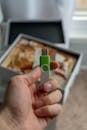 Hand Holding USB Drive with Memory Box in Background