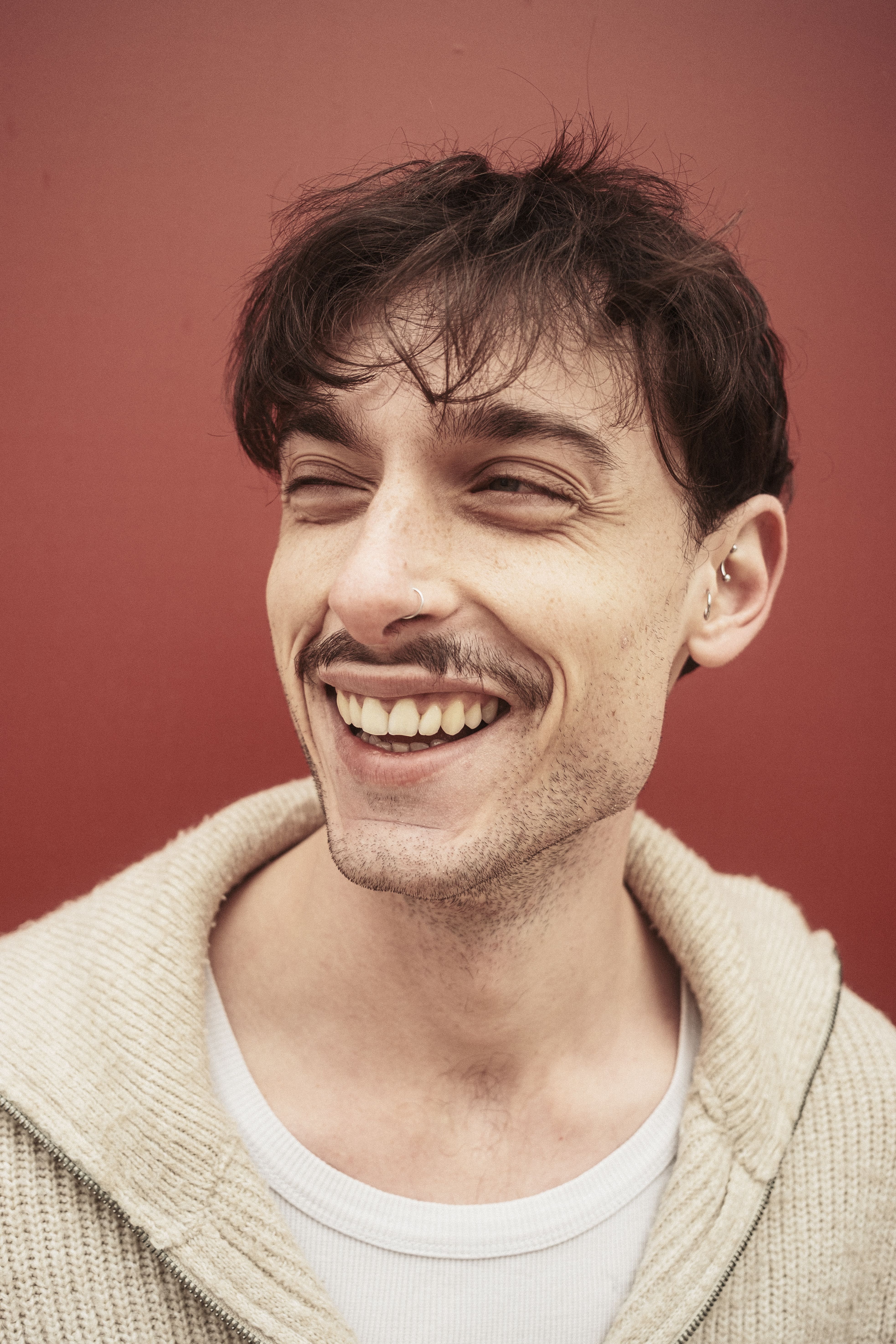 Portrait of a young man smiling with joy against a vibrant red background.
