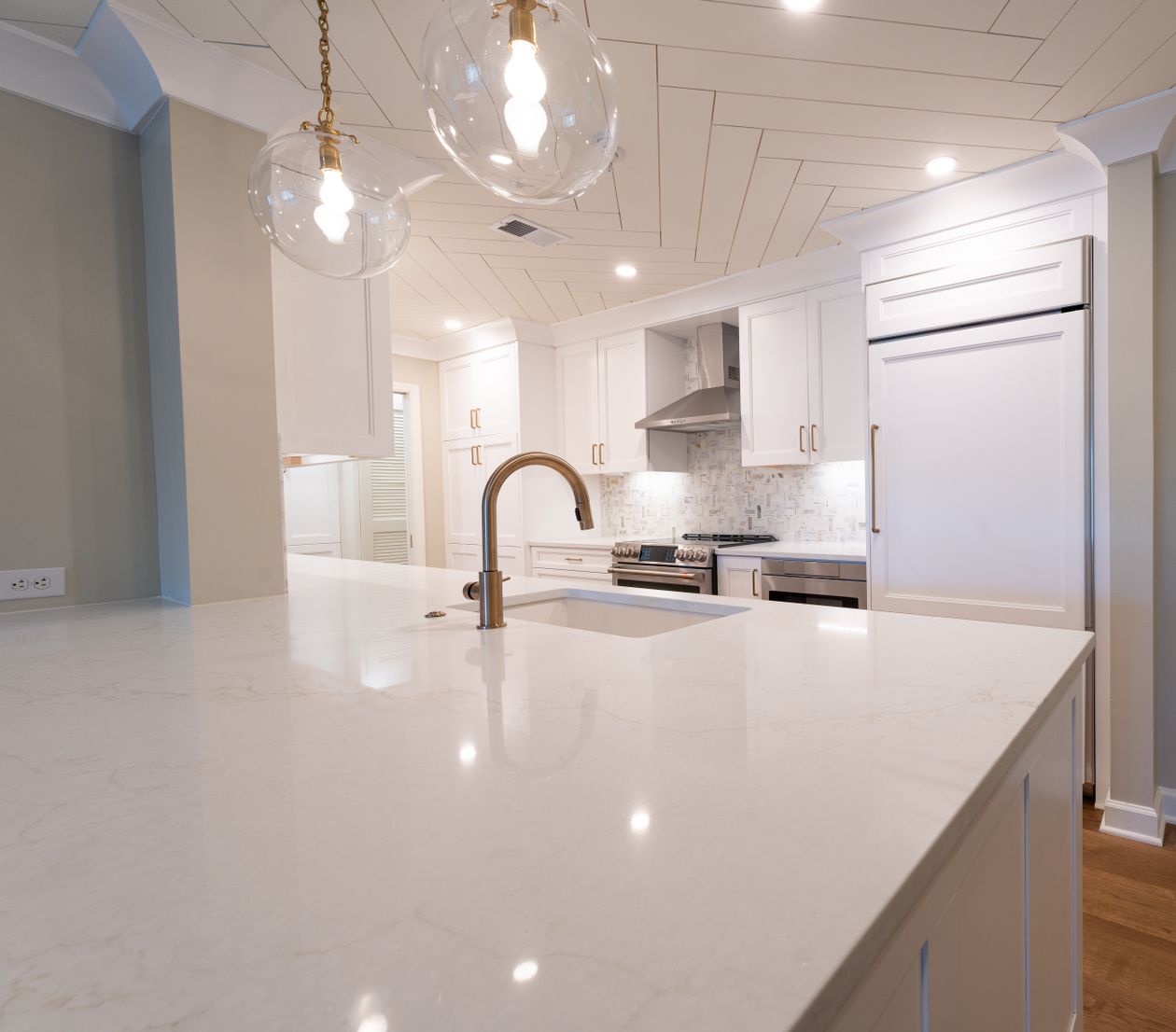 White kitchen with a champagne-gold faucet and gold cabinet pulls