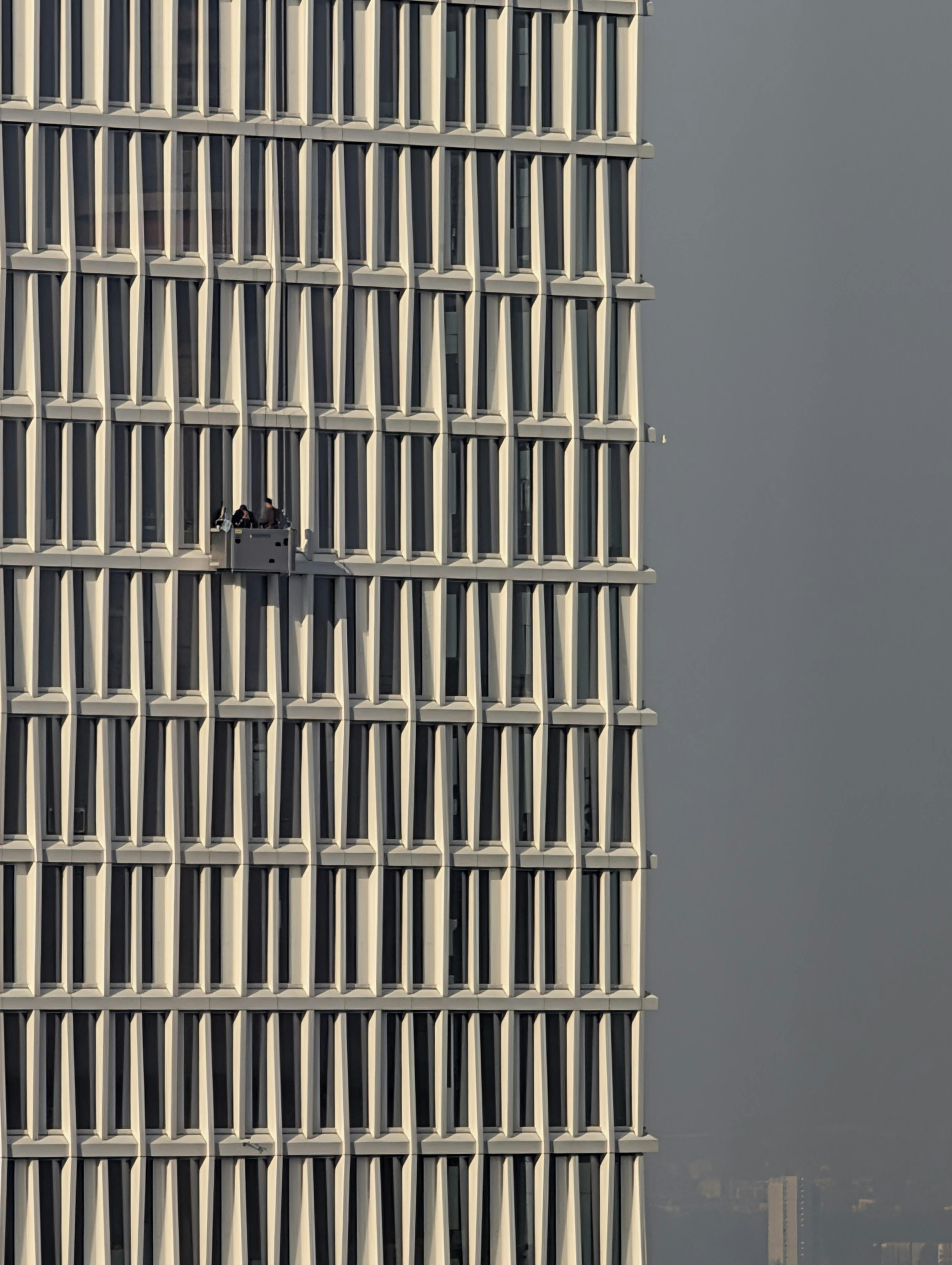 Kostenlos Fensterputzer arbeiten an der Fassade eines modernen Wolkenkratzers und geben so den Blick auf die urbane Architektur frei. Stock-Foto