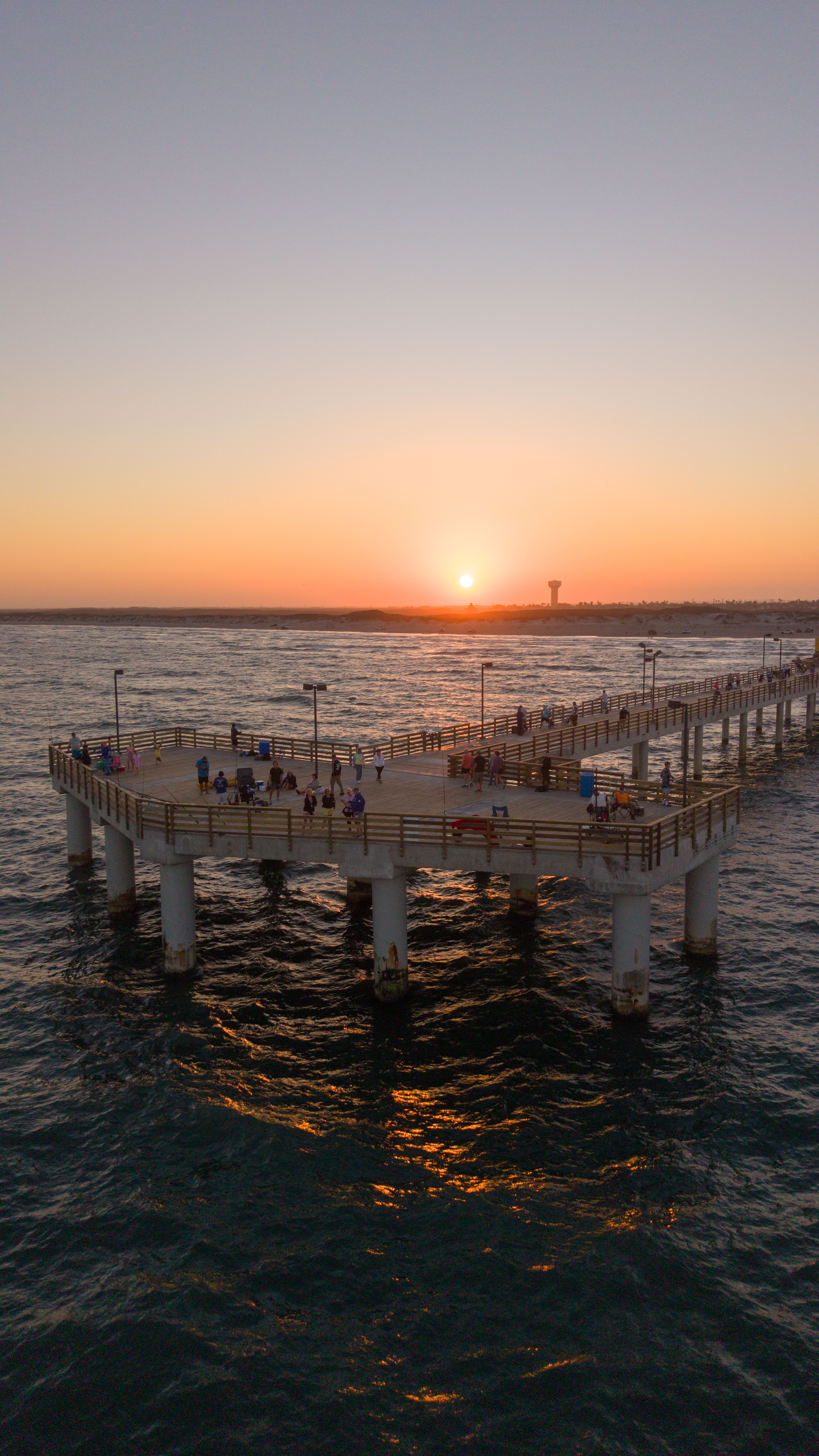 Pôr do sol deslumbrante em pier próximo ao mar, simbolizando o dia de Corpus Christi com clima de tranquilidade