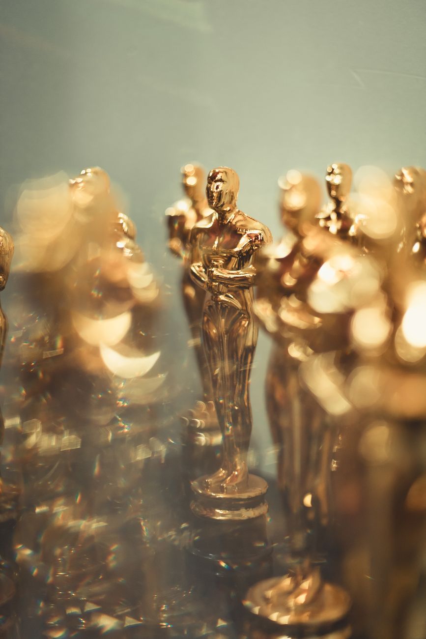 Close-up van meerdere gouden trofeeën die lijken op Oscars en symbool staan ​​voor prestatie.