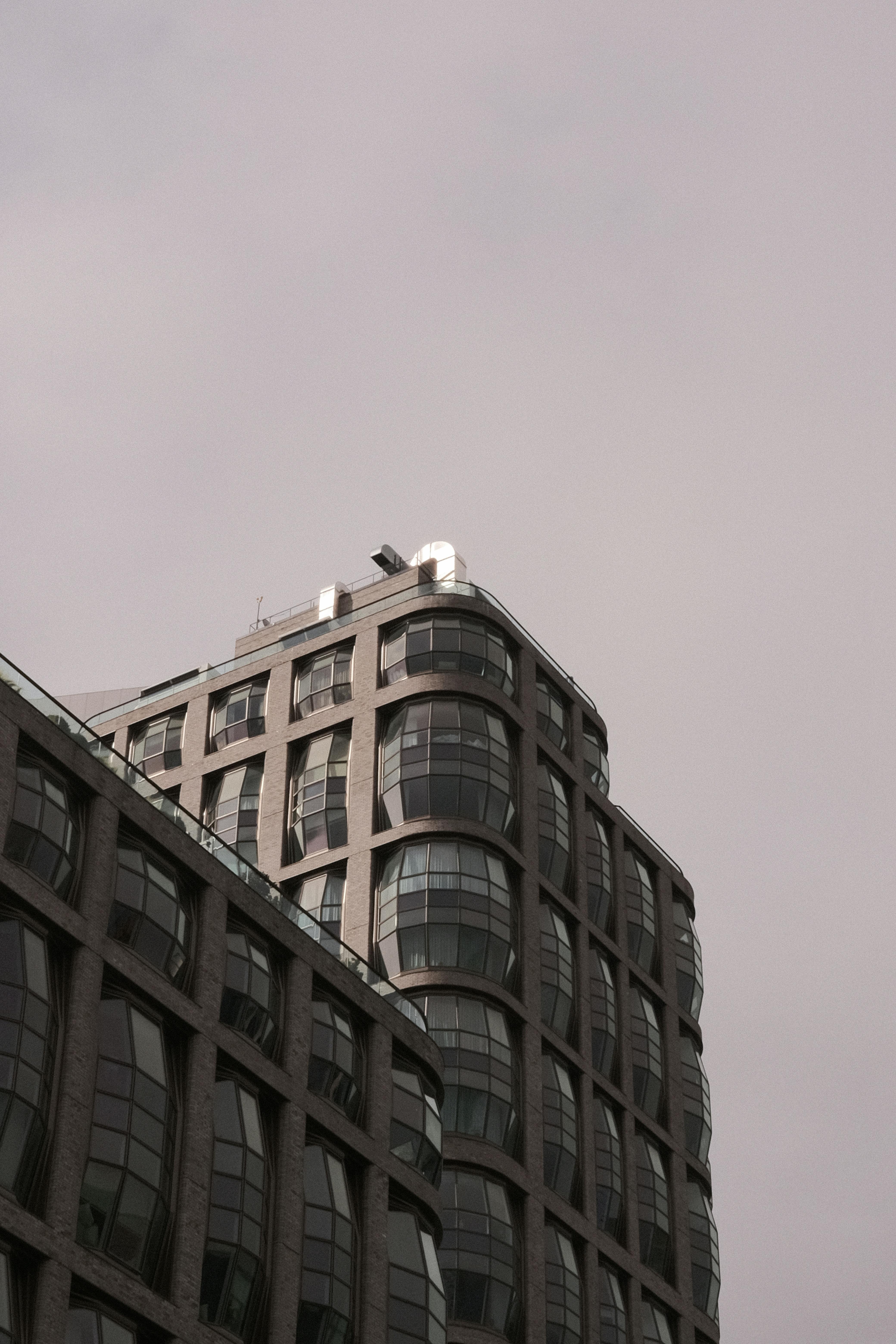 gratis Een moderne wolkenkrabber in New York City met een uniek gebogen ontwerp tegen een bewolkte hemel. Stockfoto