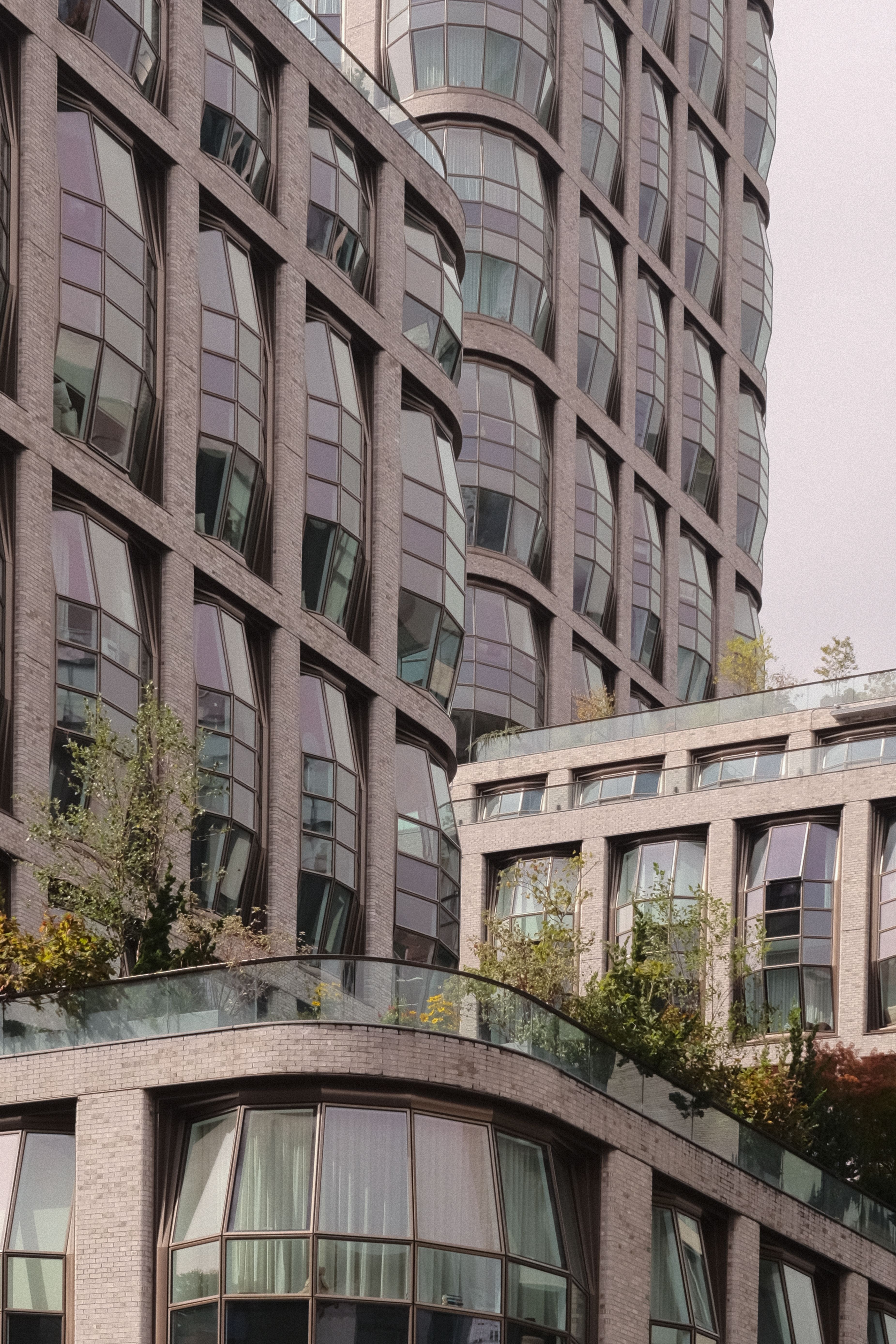 Curved glass buildings with lush greenery in NYC's urban landscape.