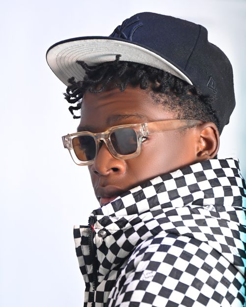 Free Portrait of a young black man wearing sunglasses, a checkered jacket, and a cap. Fashionable and modern style. Stock Photo