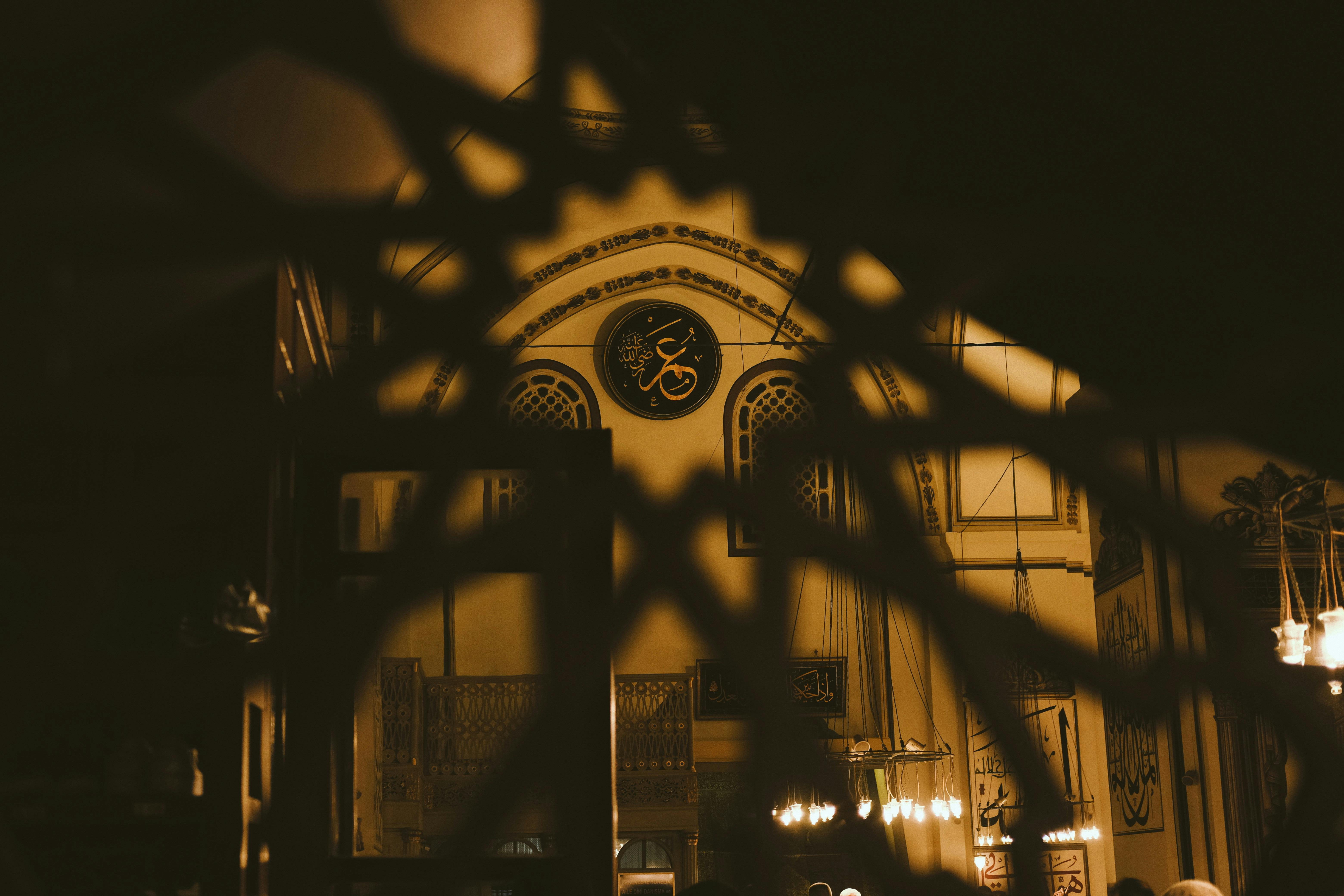 gratis Het gedetailleerde interieur van een historische moskee met warme verlichting en decoratieve islamitische kalligrafie. Stockfoto