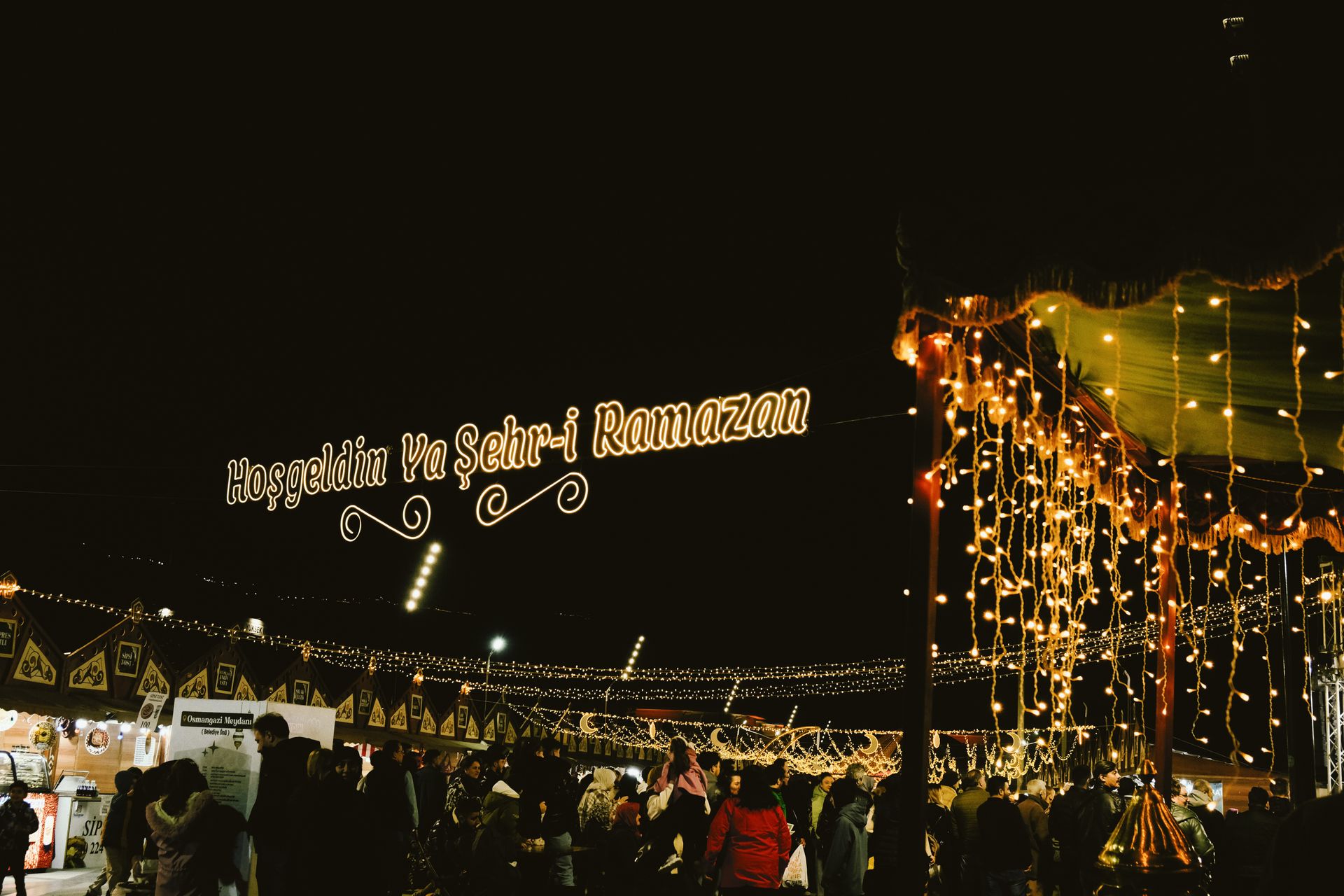 Night market during Ramadan, adorned with festive lights and crowds celebrating under illuminated si