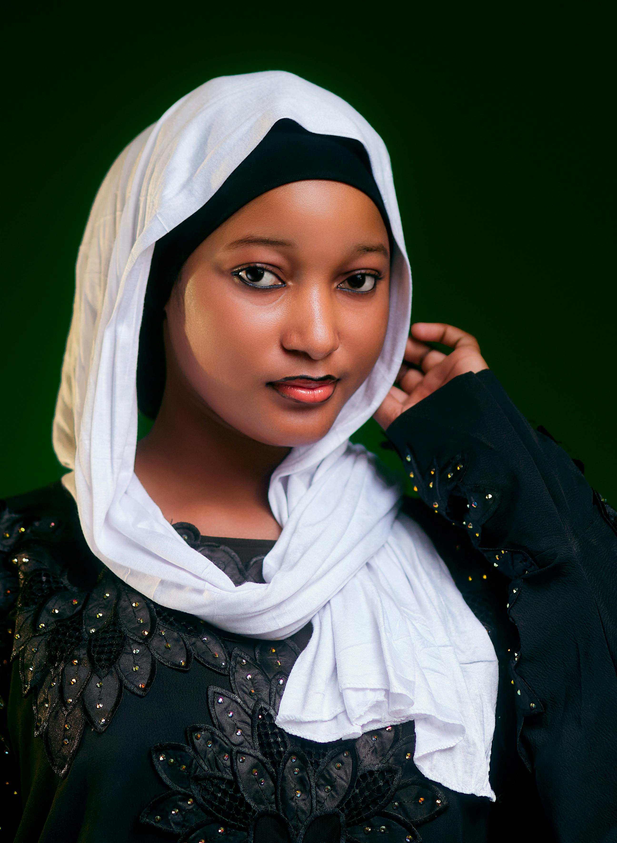 Elegant portrait of a woman wearing a hijab with a green background in Abuja, Nigeria.