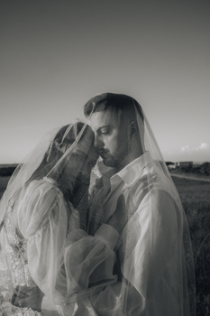 A tender black and white wedding photo of a couple in a serene outdoor setting.