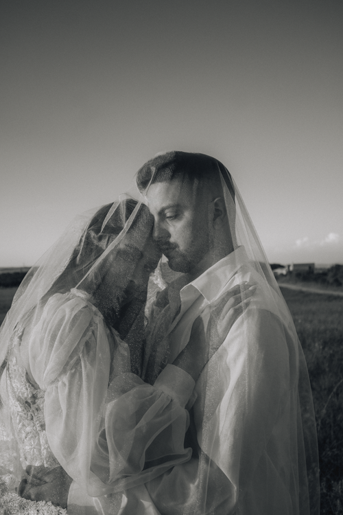 Free A tender black and white wedding photo of a couple in a serene outdoor setting. Stock Photo