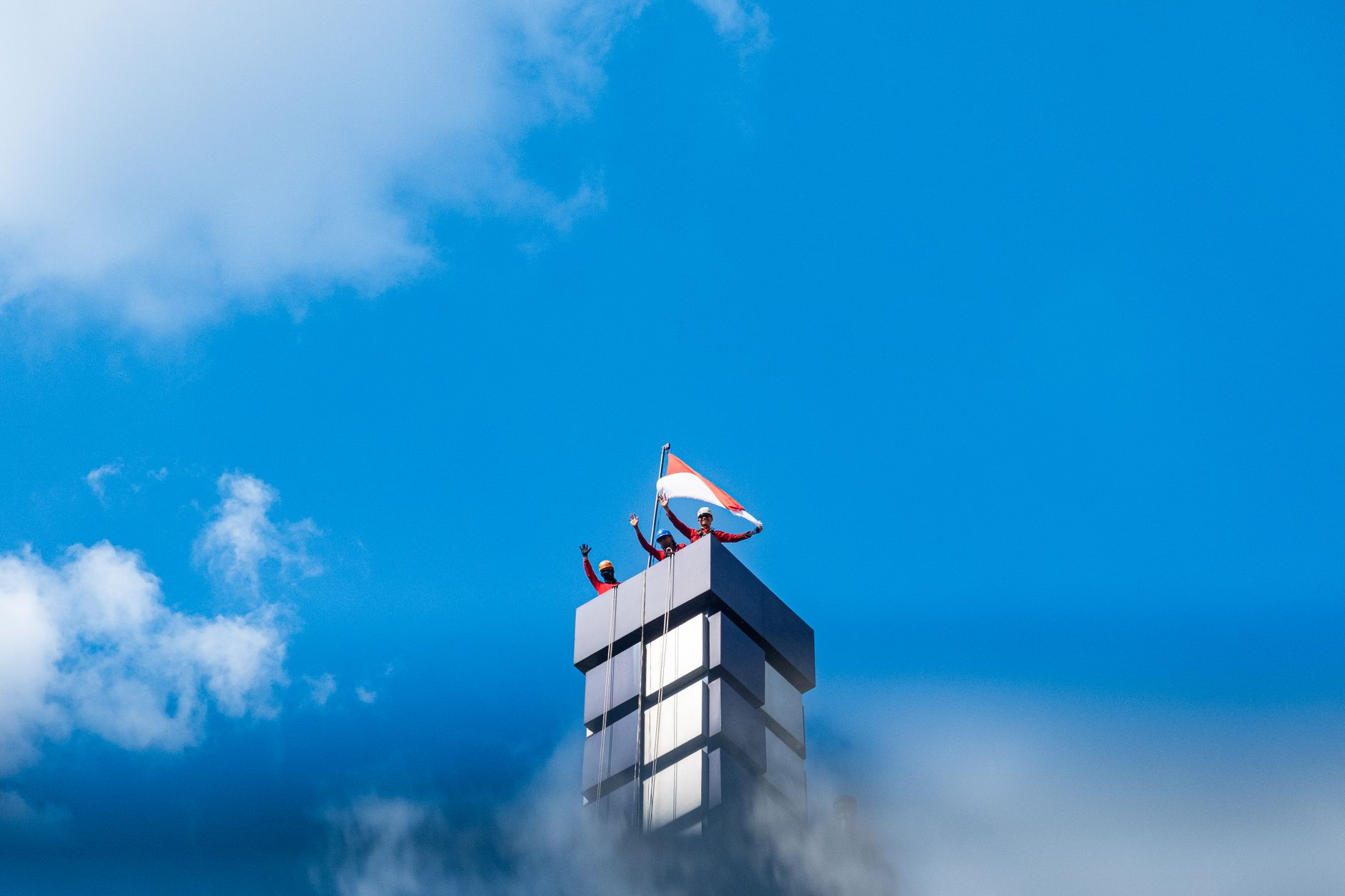High view of Indonesian flag on a tower with clear blue skies in Bandung, Indonesia.
