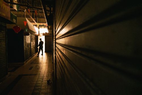 Free A mysterious silhouette in a shadowed passageway with warm lighting, captured in Bandung, Indonesia. Stock Photo
