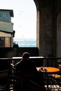 Man enjoying coffee with a view of the sea in historic Istanbul. Perfect blend of urban and natural beauty.