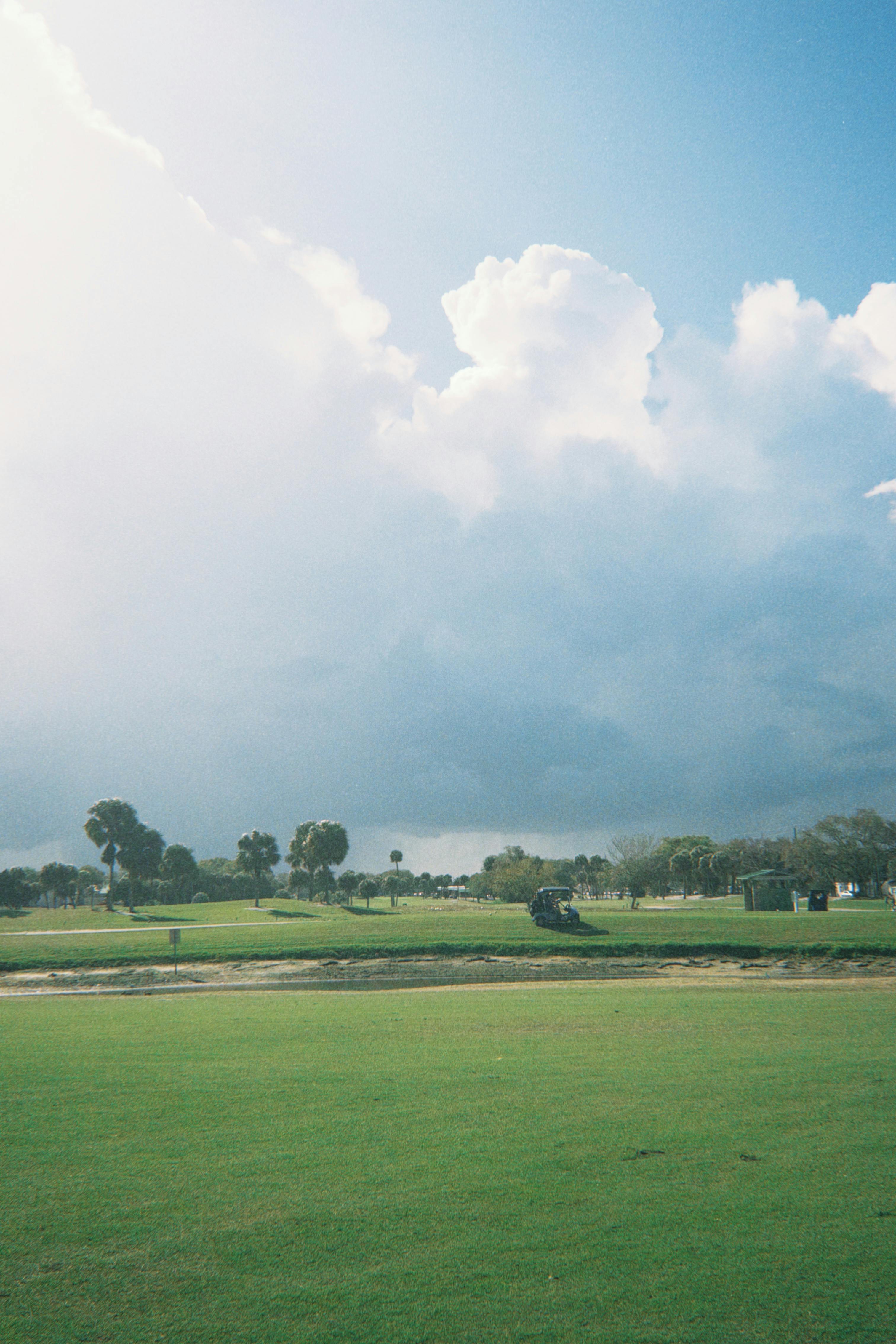 De franc Un vast camp de golf amb una exuberant gespa verda i un cel ennuvolat, que crea un entorn exterior tranquil. Foto d'estoc